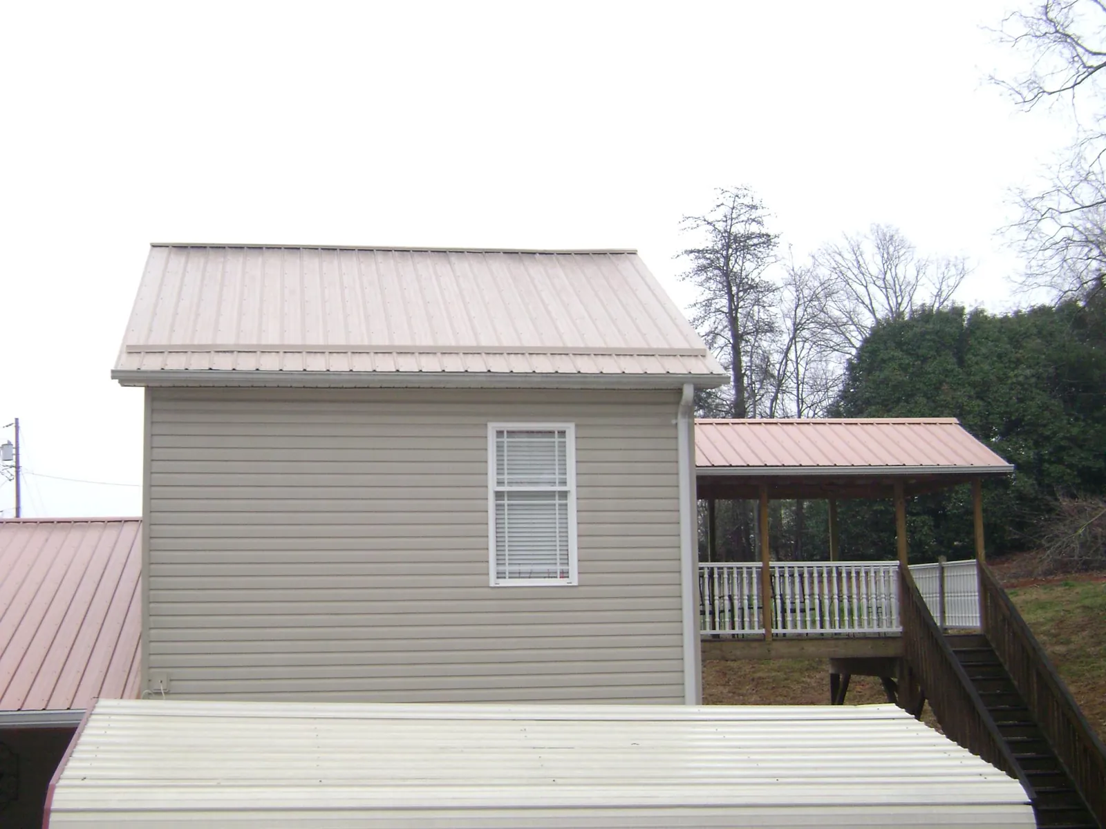 Tan metal roofs on a two story addition and attached porch, from a Roof Replacement job in Aiea