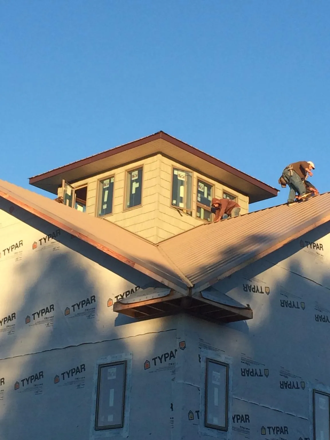 Roofers working around a rooftop cupola on a new metal roof at sunset — Roof Waterproofing in Aiea by Roofing Brothers
